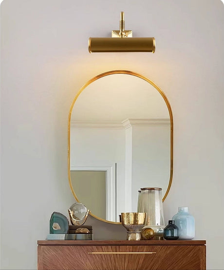 Brass tube above an arched mirror on a walnut dresser with glassware