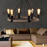 Chandelier lit above a pale sofa and a rug in a concrete walled room