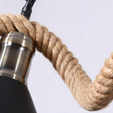 A metal socket clamped to the rope bound ring, seen against plain ground