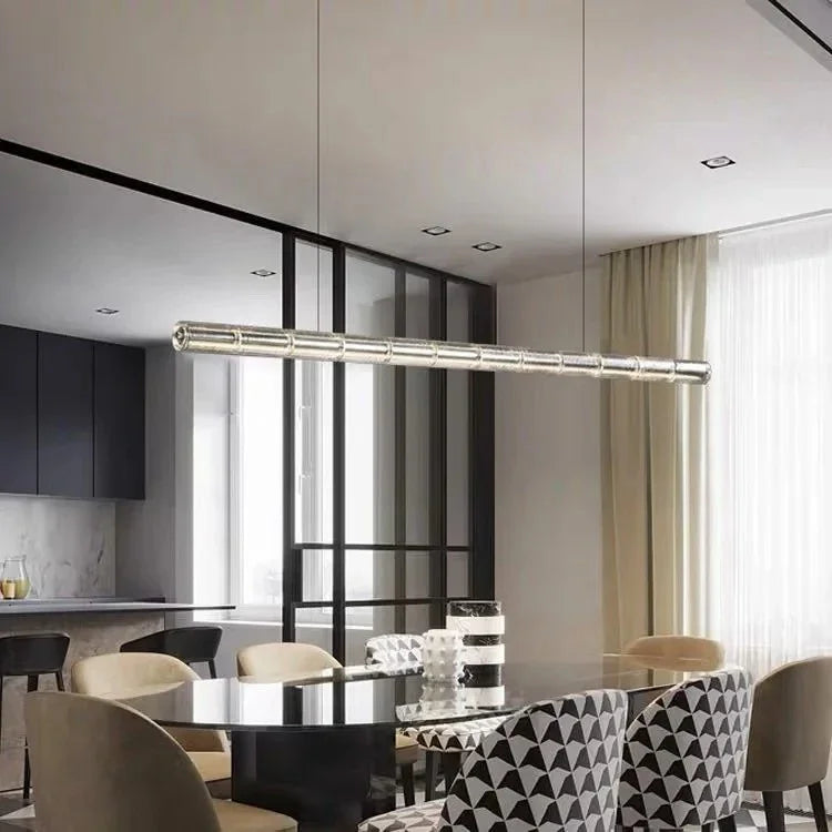 The ribbed glass bar lit above a long dining table with a window behind