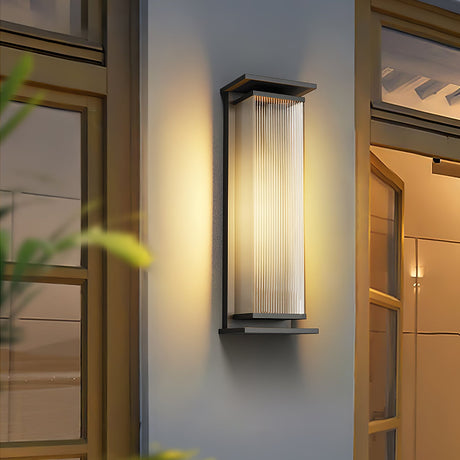 The light lit beside a timber framed doorway with planting in front