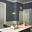 Two clear glass dome pendants hanging over a console table against a blue gray wall