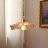 An amber lotus shade lit beside a framed landscape on a pale wall