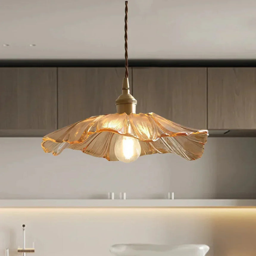 An amber lotus shade lit above a counter with a lit shelf behind