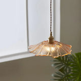An amber shade lit beside a window with a green plant to one side