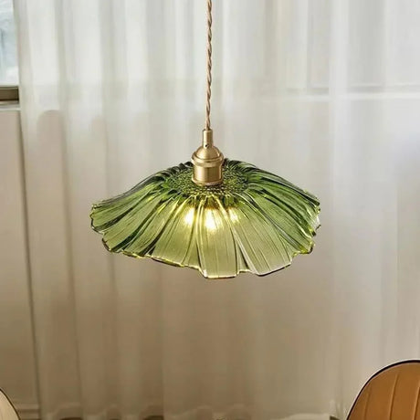 A green lotus shade lit in front of a sheer curtain in a pale room
