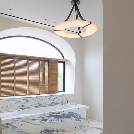 The lit ring above a marble bath under an arched window with blinds