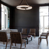 The lit ring in a dark dining room with chairs and tall windows behind