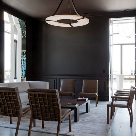 The lit ring in a dark dining room with chairs and tall windows behind