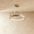 A shallow gold crown ring set with leaf shaped crystals, lit close to the ceiling