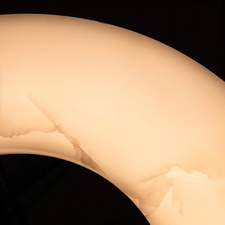 The curve of the lit stone ring, veining showing through the alabaster