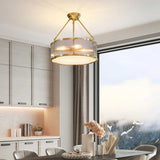 Brass drum above a kitchen island with pale cabinets and a window behind