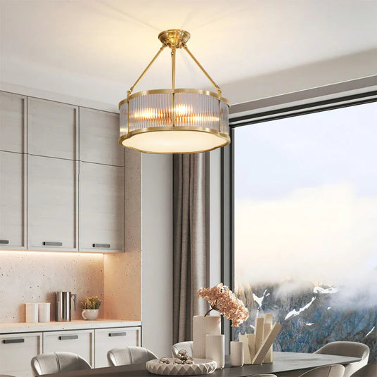Brass drum above a kitchen island with pale cabinets and a window behind