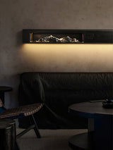 Black panel lit at night above a dark headboard, the wall washed warm
