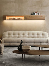 Light wood panel lit above a sofa with small objects on its top edge