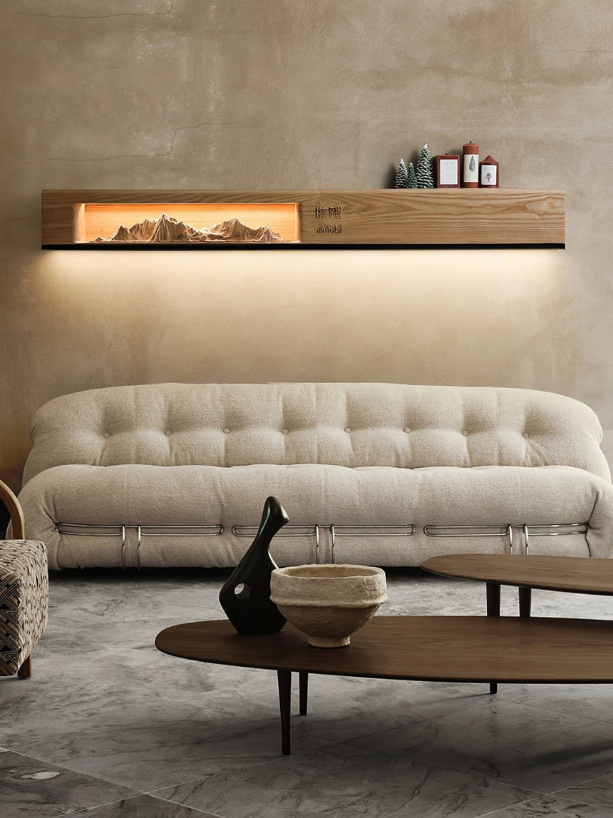 Light wood panel lit above a sofa with small objects on its top edge
