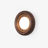 Low profile wall sconce, a rounded wood ring with a lit disc at its center