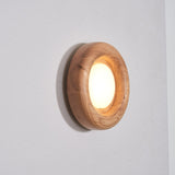 Light wood ring lit warm, the round diffuser sitting inside the rounded rim