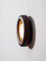 The ring in profile against a pale wall showing its shallow depth