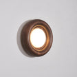 Walnut ring lit warm, the round diffuser recessed inside the turned rim