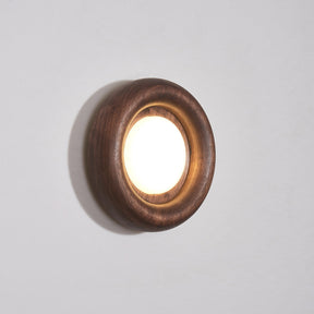 Walnut ring lit warm, the round diffuser recessed inside the turned rim