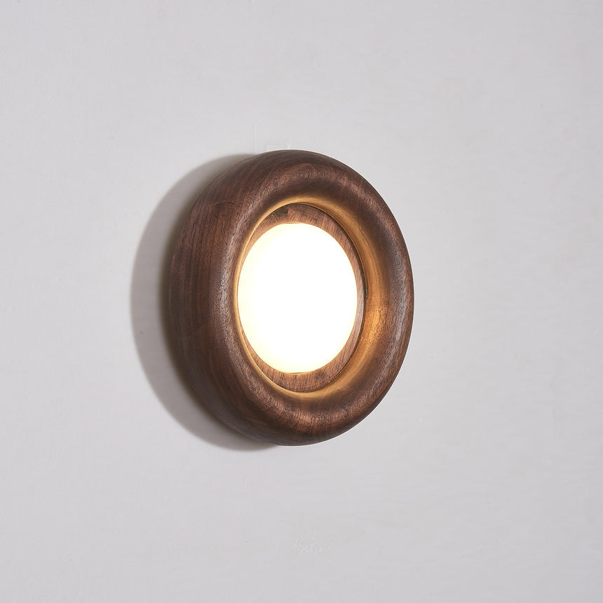 Walnut ring lit warm, the round diffuser recessed inside the turned rim