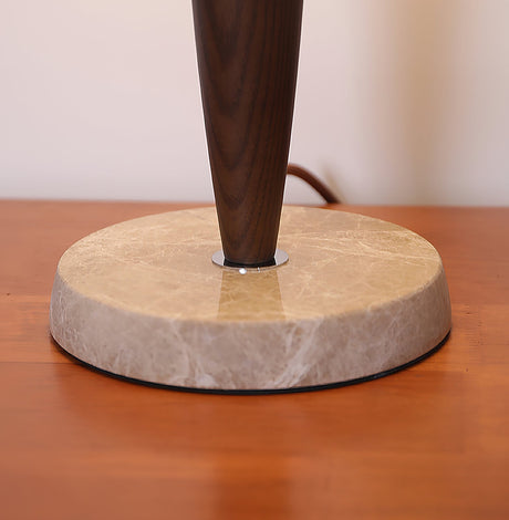 Close view of the veined marble disc base and the walnut stem