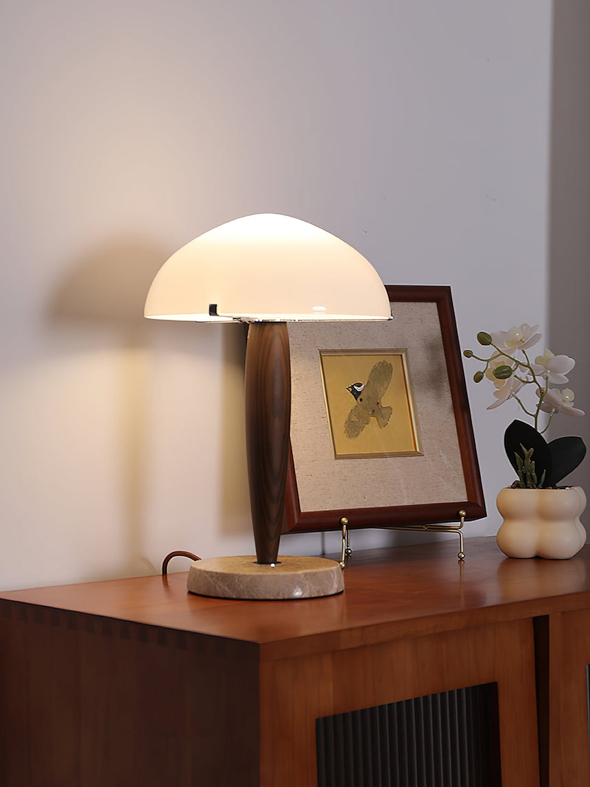 Marble base table lamp lit beside a framed picture and orchids