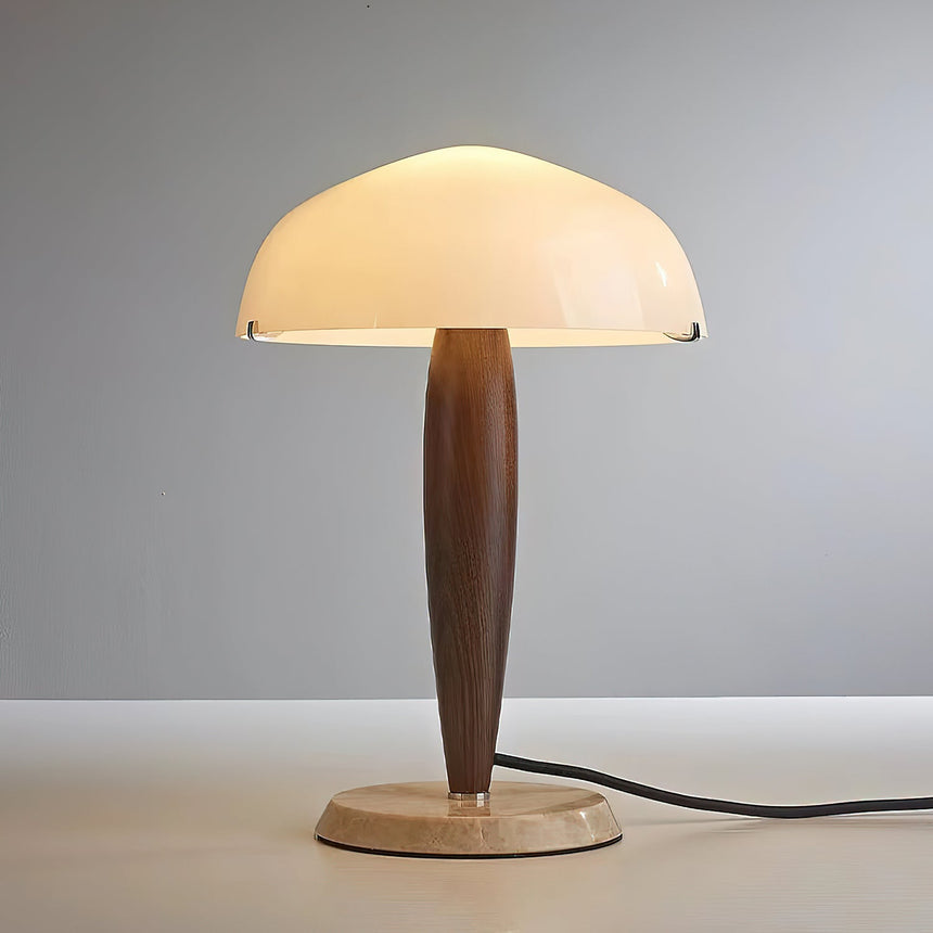 Marble base table lamp lit and seen from the front on a pale ground