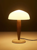 Marble base table lamp lit against a dark ground, the dome glowing