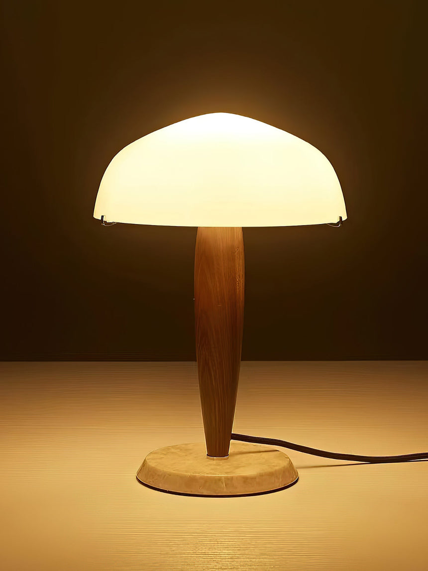 Marble base table lamp lit against a dark ground, the dome glowing