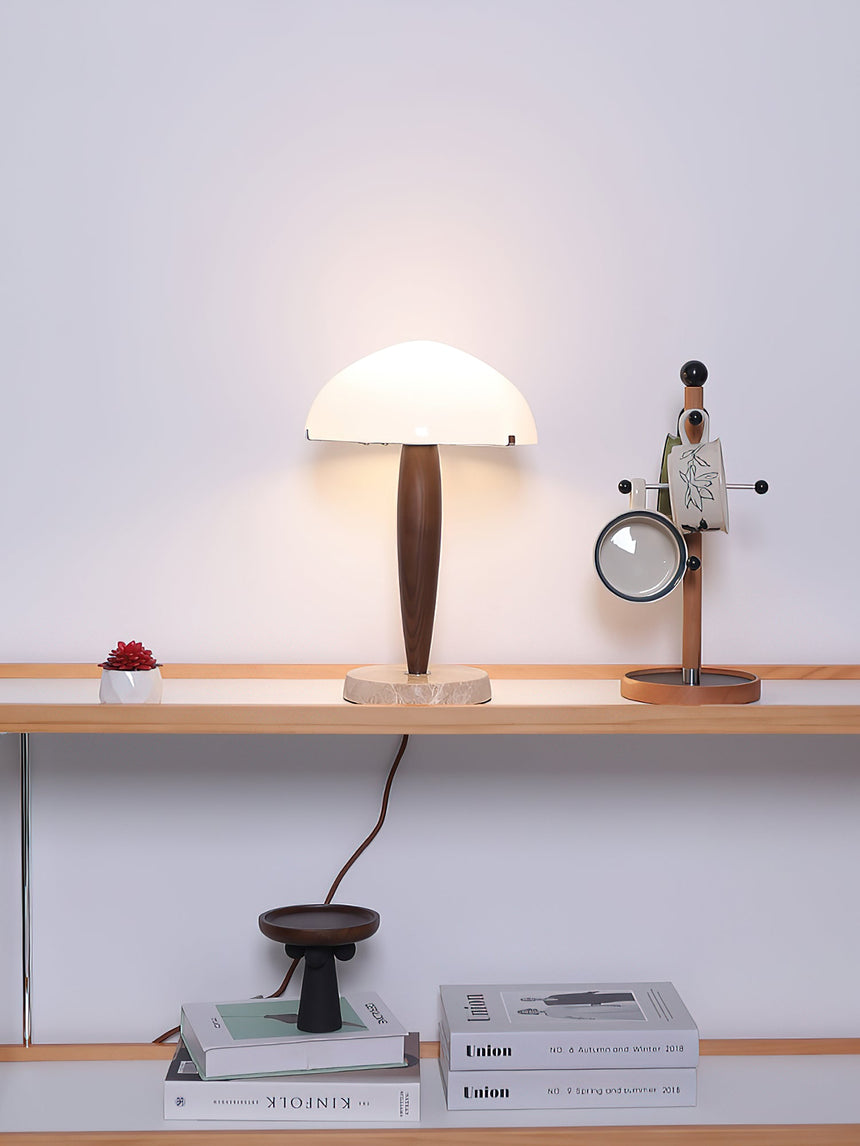 Marble base table lamp lit on a shelf beside books and objects