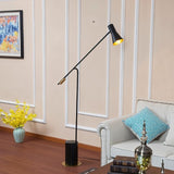 The lit lamp reaching over a sofa with a cushion and a low side table beside it