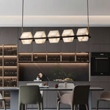 Lit stone cubes above a kitchen counter with stools and a wine wall behind