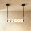 A long black bar carrying five lit alabaster cubes below a rectangular plate