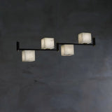 Four lit alabaster cubes in a row on a slim black bar below a plate