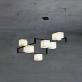 A compact staggered set of lit stone cubes on black arms and cables