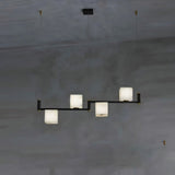 Three lit alabaster cubes stepped on a short black arm, dark wall behind
