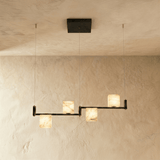 Three lit alabaster cubes stepped along a black arm on thin cables
