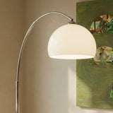 The lit white dome and chrome arm beside a framed green painting on a wall