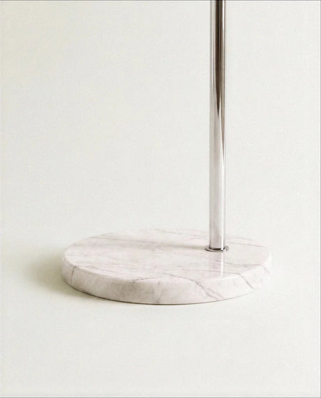 The round white marble base and the chrome rod that rises out of its middle