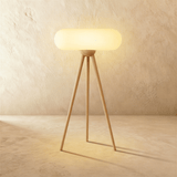 The same tripod in natural wood, the pale capsule shade lit above three legs