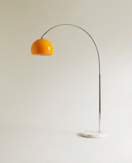The same curved chrome arm with the orange glass dome, marble base on the ground