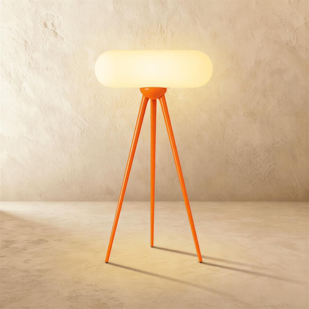 An orange wood tripod carrying a wide rounded capsule shade lit from within