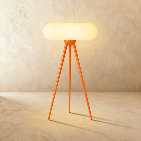 An orange wood tripod carrying a wide rounded capsule shade lit from within