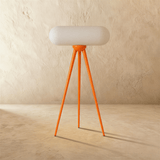 The orange tripod unlit, the capsule shade resting across the top of the legs
