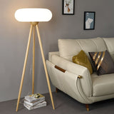 The natural wood lamp lit beside a cream sofa with cushions, artwork and books