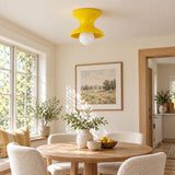 Yellow spool ceiling light above a round dining table with pale chairs