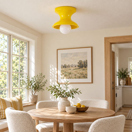 Yellow spool ceiling light above a round dining table with pale chairs