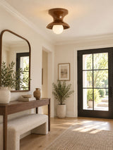 Red spool ceiling light in an entryway with an arched mirror and a bench